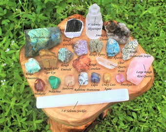 May include: A collection of 20 different types of rough and polished crystals and stones, including amethyst, rose quartz, tiger eye, and selenite. The crystals are arranged on a wooden surface with labels identifying each type.