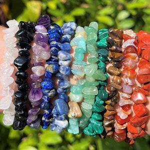 May include: A stack of 10 bracelets made with chipped gemstone beads. The bracelets are in various colors, including white, black, purple, blue, green, brown, orange, and red.