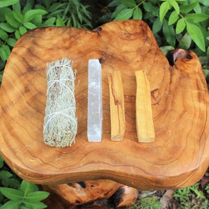 May include: A set of four smudging sticks on a wooden surface. The sticks are white, gray, brown, and light brown. The sticks are used for smudging ceremonies.