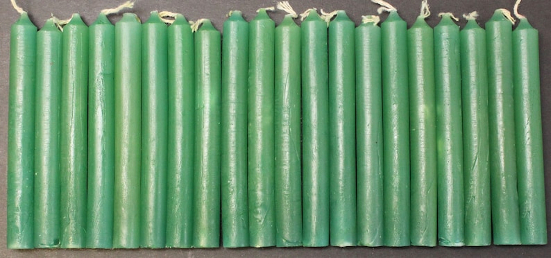 May include: A set of 24 green taper candles. The candles are approximately 6 inches long and are made of a smooth, waxy material.