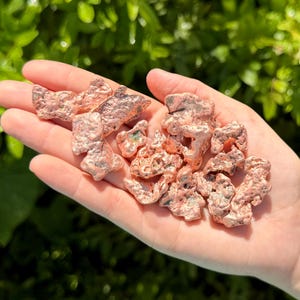 May include: A collection of raw, metallic copper nuggets with irregular, textured surfaces and a distinct reddish-brown hue. These small, solid mineral pieces exhibit natural, jagged formations and a reflective, shiny finish across their uneven shapes.