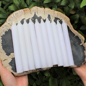 May include: A set of ten white taper candles arranged on a petrified wood slice. The candles are approximately 7 inches long.