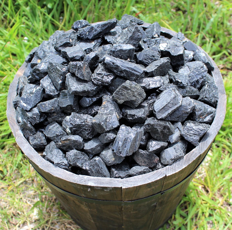 May include: A wooden bowl filled with black tourmaline crystals. The crystals are rough and have a natural, unpolished look.