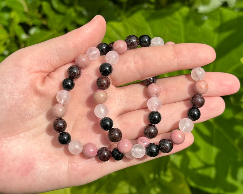 May include: Two bracelets made with pink, black, and brown beads. The bracelets are made with natural stones.