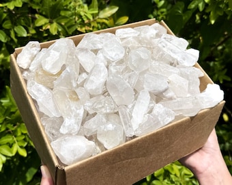 Könnte beinhalten: Eine Schachtel gefüllt mit einer großen Menge an klaren Quarzkristallen. Die Kristalle sind in verschiedenen Größen und Formen, einige haben eine leicht trübe Optik.