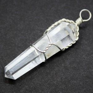 May include: A clear quartz crystal point pendant wrapped in silver wire. The pendant has a simple loop for attaching to a chain or cord.