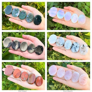 May include: A collection of eight polished palm stones in various colours and patterns, including moss agate, opalite, pyrite, rainbow moonstone, red jasper, and rose quartz.
