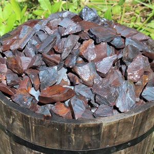 May include: A wooden bucket filled with a large quantity of dark gray and reddish-brown hematite stones.