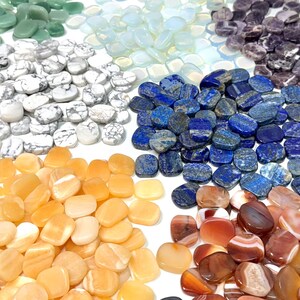 May include: A collection of polished gemstones in various colors, including green, white, blue, purple, orange, and red. The stones are oval-shaped and arranged in a circular pattern, showcasing their natural textures and hues. Ideal for jewelry making or crystal healing.