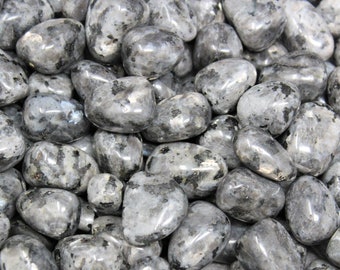May include: A close-up of a pile of tumbled labradorite stones. The stones are a mix of gray and black with a shimmery, iridescent finish.