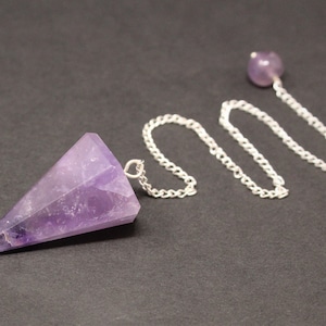 May include: Amethyst crystal pendulum with a silver chain. The pendulum is a pointed, purple crystal.