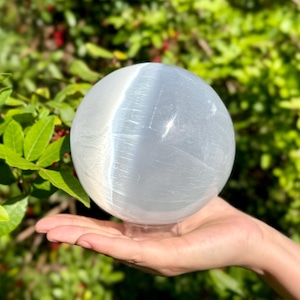 Op de afbeelding: Een grote, witte selenietbol met een glad, gepolijst oppervlak. De bol staat op een heldere standaard.