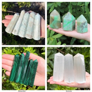 May include: A collection of four crystal towers including pale blue-grey aquamarine, green and brown garnierite, deep green banded malachite, and translucent white selenite, each shaped into a pointed hexagonal column for display.