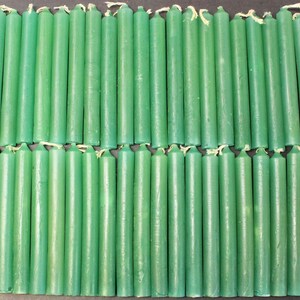 May include: A group of 48 green taper candles arranged in two rows. The candles are approximately 6 inches long and have a smooth, matte finish.