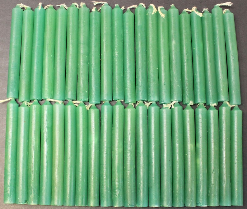 May include: A group of 48 green taper candles arranged in two rows. The candles are approximately 6 inches long and have a smooth, matte finish.