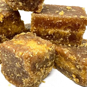 Peut inclure: Gros plan sur des cubes de sucre roux empil&eacute;s. Les cubes pr&eacute;sentent une texture cristalline et une riche couleur brun dor&eacute;. La surface est l&eacute;g&egrave;rement rugueuse, sugg&eacute;rant un produit naturel. L'image met en valeur la texture et la couleur.