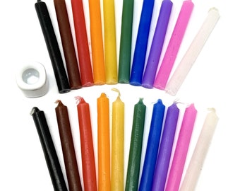 May include: A set of 18 small, thin candles in various colors, including black, brown, red, orange, yellow, green, blue, purple, pink, and white. The candles are arranged in a semi-circle, with a small white candle holder in the center.