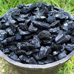 May include: A wooden bowl filled with black tourmaline crystals. The crystals are rough and have a natural, unpolished look.