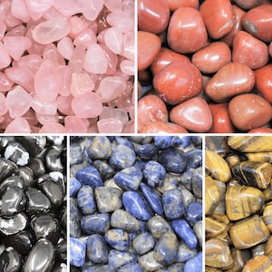 May include: A collection of tumbled stones in various colors, including pink, red, black, blue, and brown. The stones are smooth and polished, and they are arranged in a grid pattern.