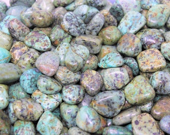 May include: A collection of tumbled turquoise stones. The stones are a mix of blue, green, and brown colors. They are smooth and polished.