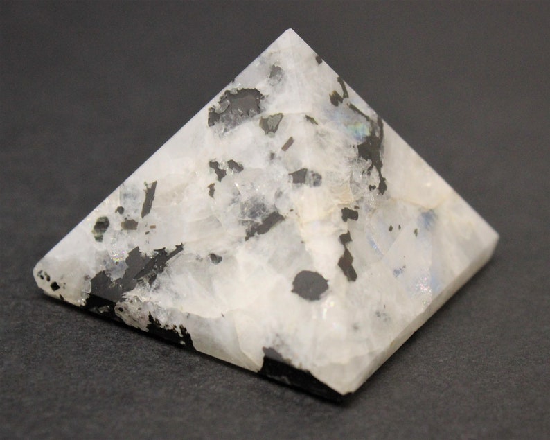 Puede incluir: Un objeto decorativo en forma de pir&aacute;mide hecho de piedra moteada blanca y negra. La pir&aacute;mide tiene una base plana y cuatro lados triangulares que se unen en un punto. La piedra tiene una superficie pulida y lisa.
