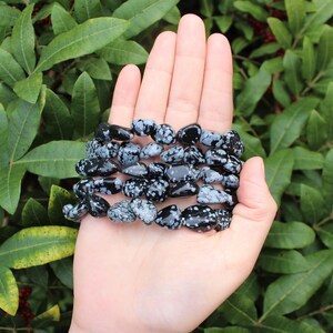 May include: A bracelet made of black and white snowflake obsidian beads. The bracelet is made of natural stones and is a popular choice for those who believe in the healing properties of crystals.