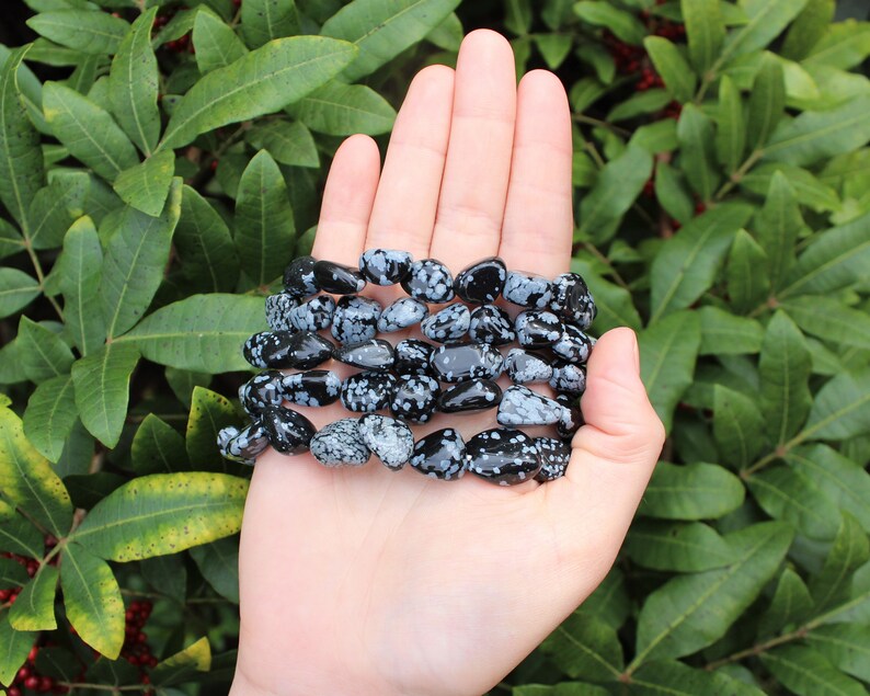 May include: A bracelet made of black and white snowflake obsidian beads. The bracelet is made of natural stones and is a popular choice for those who believe in the healing properties of crystals.