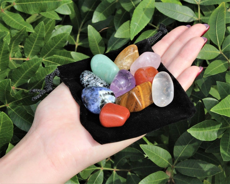 May include: A black velvet pouch filled with a variety of tumbled gemstones, including amethyst, clear quartz, tiger's eye, red jasper, and green aventurine.