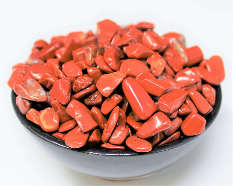 Puede incluir: Un cuenco lleno de piedras de jaspe rojo pulidas. Las piedras son lisas y pulidas, de un color rojo intenso.