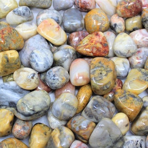 May include: A collection of tumbled stones with a variety of colors and patterns, including yellow, brown, gray, and white. The stones are smooth and polished, and they have a natural, organic look.