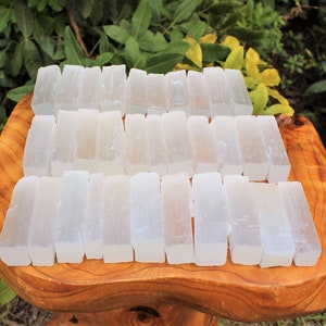 Bulk lot of 2.5" - 3" selenite sticks on a display table.