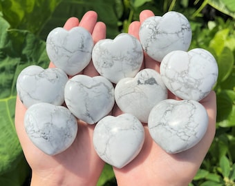 Puede incluir: Una colección de diez piedras de howlite en forma de corazón de color blanco. Las piedras tienen un patrón de mármol con vetas grises.