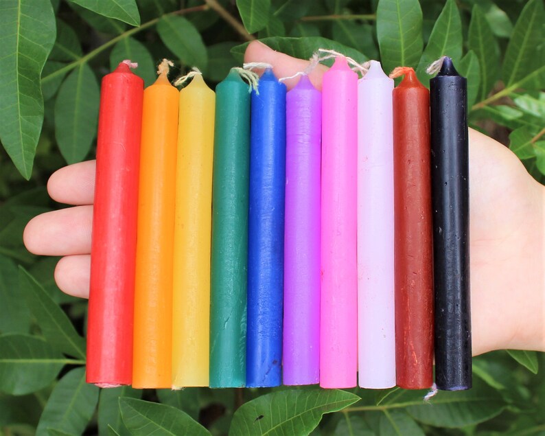 May include: A set of 10 small, thin, colored candles. The candles are arranged in a rainbow order, from red to black. The candles are about 6 inches long.