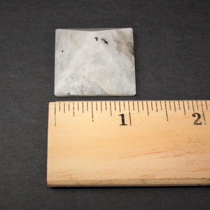 Puede incluir: Una pir&aacute;mide cuadrada de piedra de color claro con una regla al lado. La pir&aacute;mide tiene un aspecto veteado blanco y gris con peque&ntilde;as motas negras. La regla es de madera y muestra medidas en cent&iacute;metros.