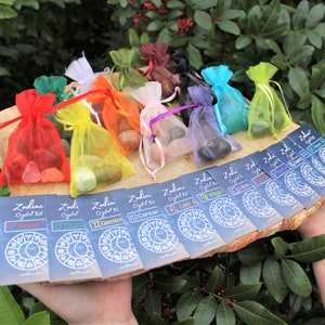 K&ouml;nnte beinhalten: Zw&ouml;lf kleine Beutel mit Kristallen, jeder in einer anderen Farbe und einer Karte mit einem Sternzeichen und den Worten "Zodiac Crystal Kit".