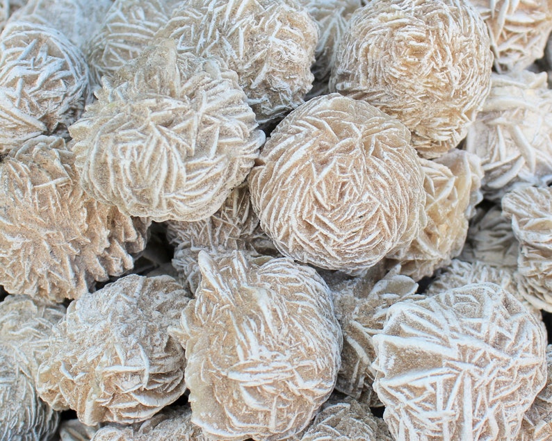 K&ouml;nnte beinhalten: Nahaufnahme eines Haufens W&uuml;stenrosen-Kristalle. Die Kristalle sind hellbraun und haben eine raue, strukturierte Oberfl&auml;che. Sie sind in einem zuf&auml;lligen Muster angeordnet.
