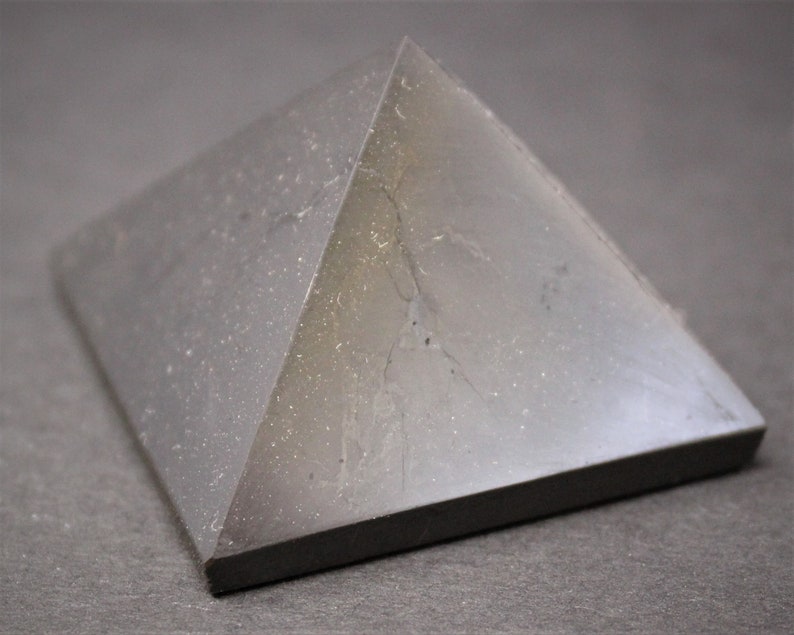 May include: A black obsidian pyramid crystal with a smooth, polished surface. The crystal has a slight sheen and is slightly translucent.