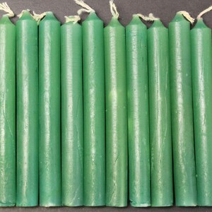 May include: A set of twelve green taper candles. The candles are approximately 6 inches long and have a smooth, glossy finish.