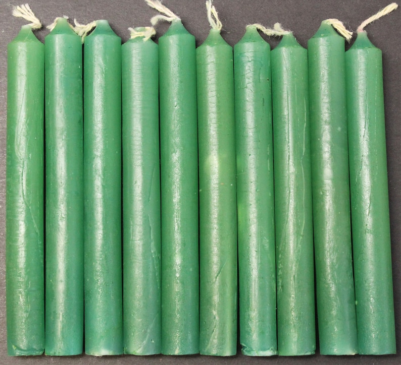 May include: A set of twelve green taper candles. The candles are approximately 6 inches long and have a smooth, glossy finish.