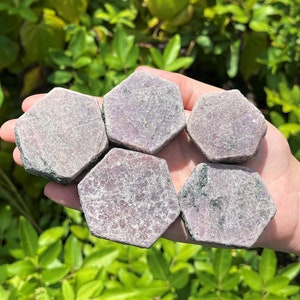 May include: Five hexagonal shaped, raw, pink and grey ruby crystals.