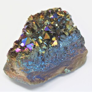 以下が含まれることがあります： 虹色のアメジストの結晶の塊で、紫、青、緑、金など様々な色をしています。結晶は自然で荒々しい形で配置されています。