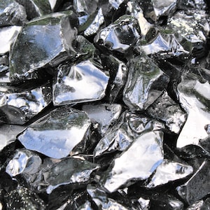 Puede incluir: Primer plano de un mont&oacute;n de rocas de obsidiana negra. Las rocas son afiladas y dentadas, y tienen una superficie brillante y vidriosa.