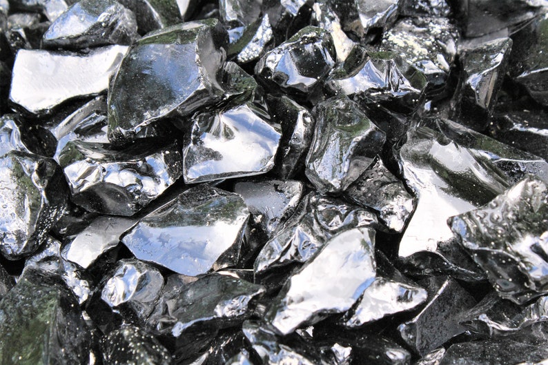 Puede incluir: Primer plano de un mont&oacute;n de rocas de obsidiana negra. Las rocas son afiladas y dentadas, y tienen una superficie brillante y vidriosa.