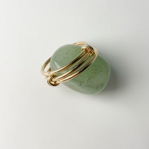 May include: A green stone ring with a gold wire wrapped around it.