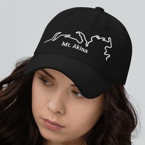May include: Black baseball cap with a white outline of a mountain range and the text "Mt. Akina". The cap is made of a soft material and has a curved brim. A stylish accessory for outdoor activities or casual wear.