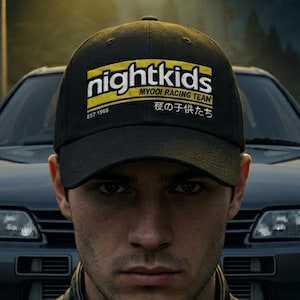 May include: A black baseball cap featuring a yellow rectangular graphic with the white text nightkids, the words MYOGI RACING TEAM, the text EST 1995, and Japanese characters printed on the front crown above the brim.