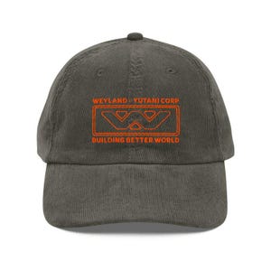 May include: A corduroy baseball cap in a muted green color. The front of the cap features the orange text "WEYLAND-YUTANI CORP" above a stylized logo and the phrase "BUILDING BETTER WORLD".