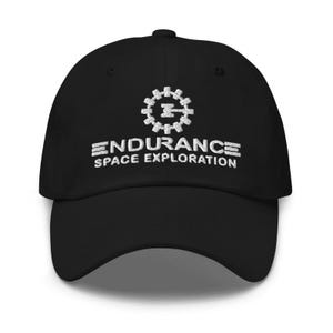 May include: Black baseball cap with white embroidered text and a gear-like logo. The text reads "ENDURANCE SPACE EXPLORATION". The cap has a curved brim and an adjustable strap.