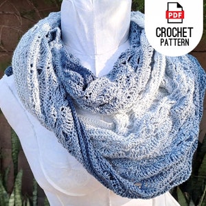 May include: A crocheted scarf in a blue ombre color pattern. The scarf is made with a delicate stitch and has a lacy appearance. The scarf is draped over a white mannequin.