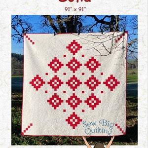 May include: A white quilt with a red geometric pattern, hanging on a clothesline outdoors. The quilt is 91 inches by 91 inches and is titled "Sofia". The quilt is designed by JoAnna Rogers and is part of the "Sew Big Quilting" collection.